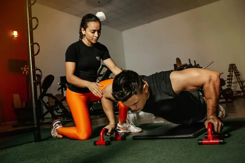 Una entrenadora corrige a un chico que hace flexiones